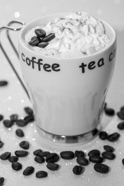 Free Elegant black and white image of a coffee cup with beans and whipped cream foam. Stock Photo