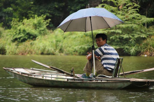 一个人撑着伞，在风景秀丽的湖面上划着独木舟，四周环绕着大自然