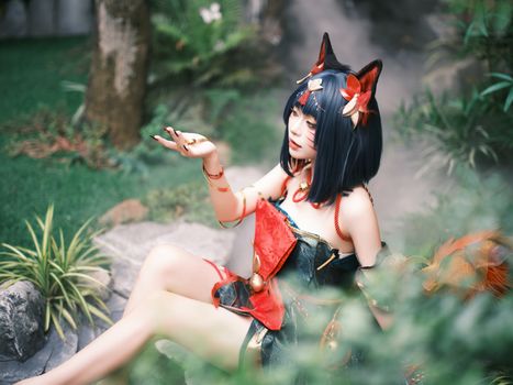 A person in fantasy cosplay poses in a lush, mystical garden.