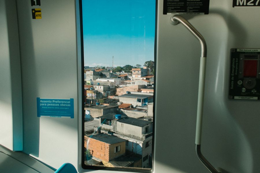 View of urban neighborhood through a train window, showcasing vibrant city life.