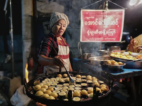 Woman cooking traditional pastries at a street market stall during the night, adding a cultural touch.