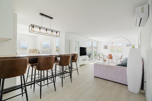 Spacious open-plan living area with modern decor and abundant natural light, showcasing stylish interior design.