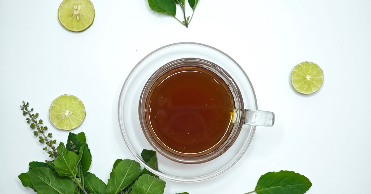 A cup of aromatic tulsi tea surrounded by fresh lime slices and basil leaves, offering a refreshing herbal beverage. - Evidence evidence guide for tulsi sleep randomized trial