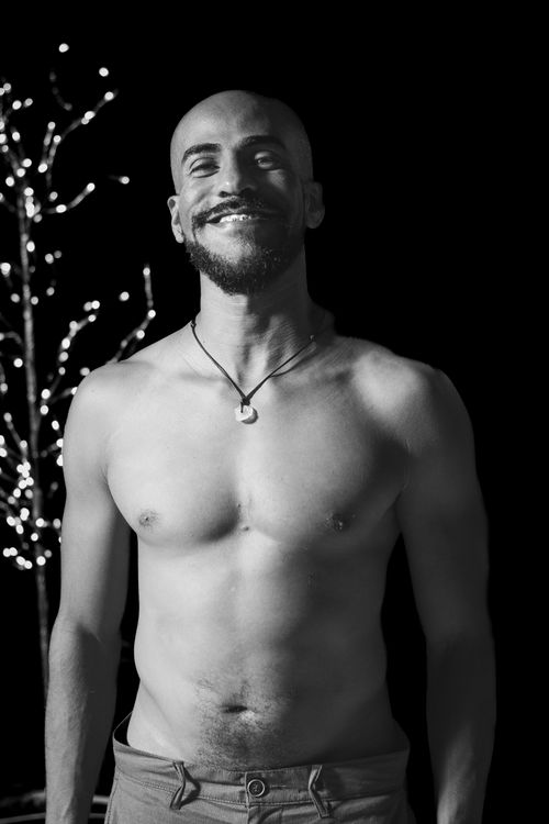 Free Portrait of a smiling shirtless man with festive lights in the background. Stock Photo