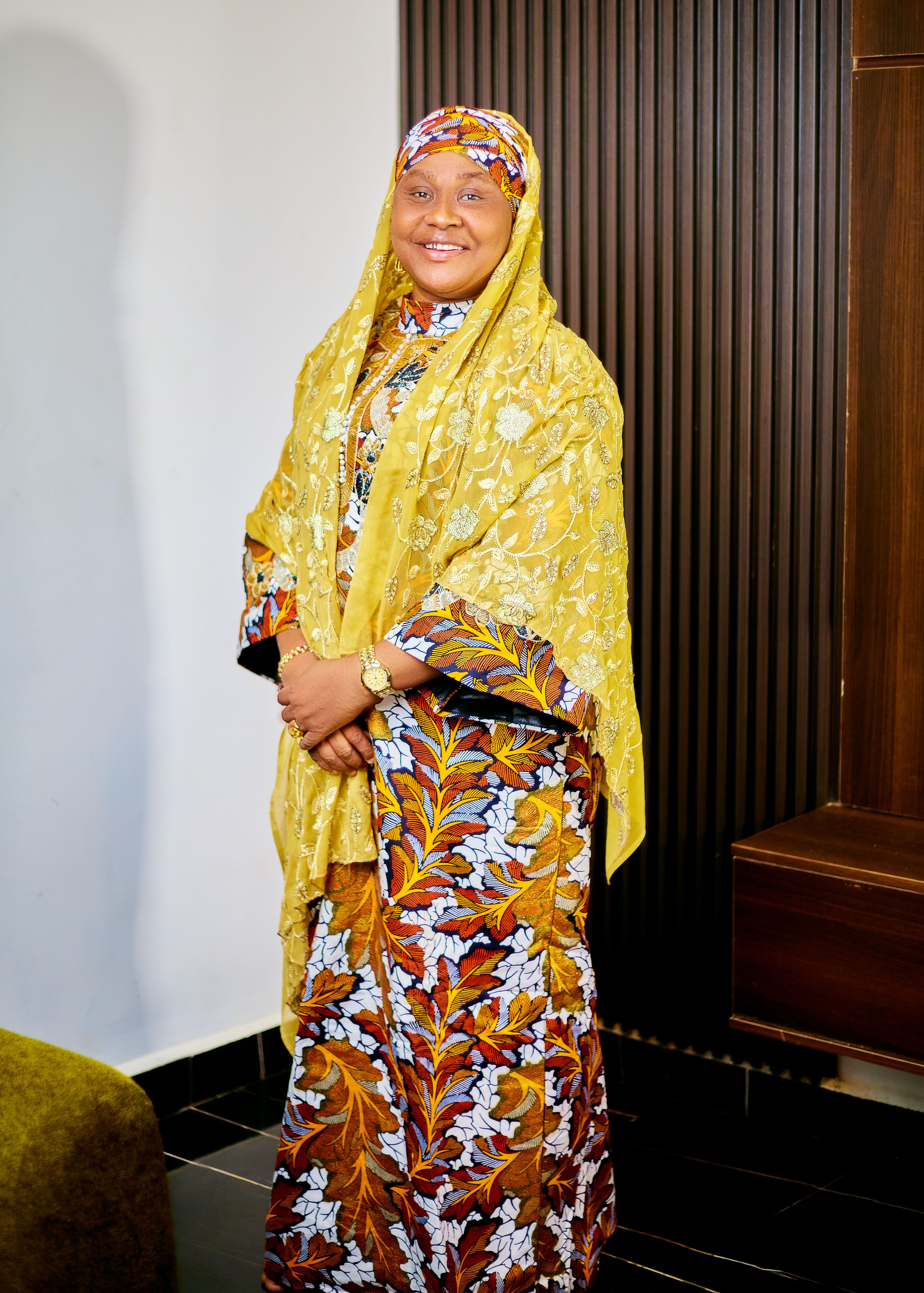 Smiling woman wearing vibrant traditional clothing indoors, exuding warmth and elegance.