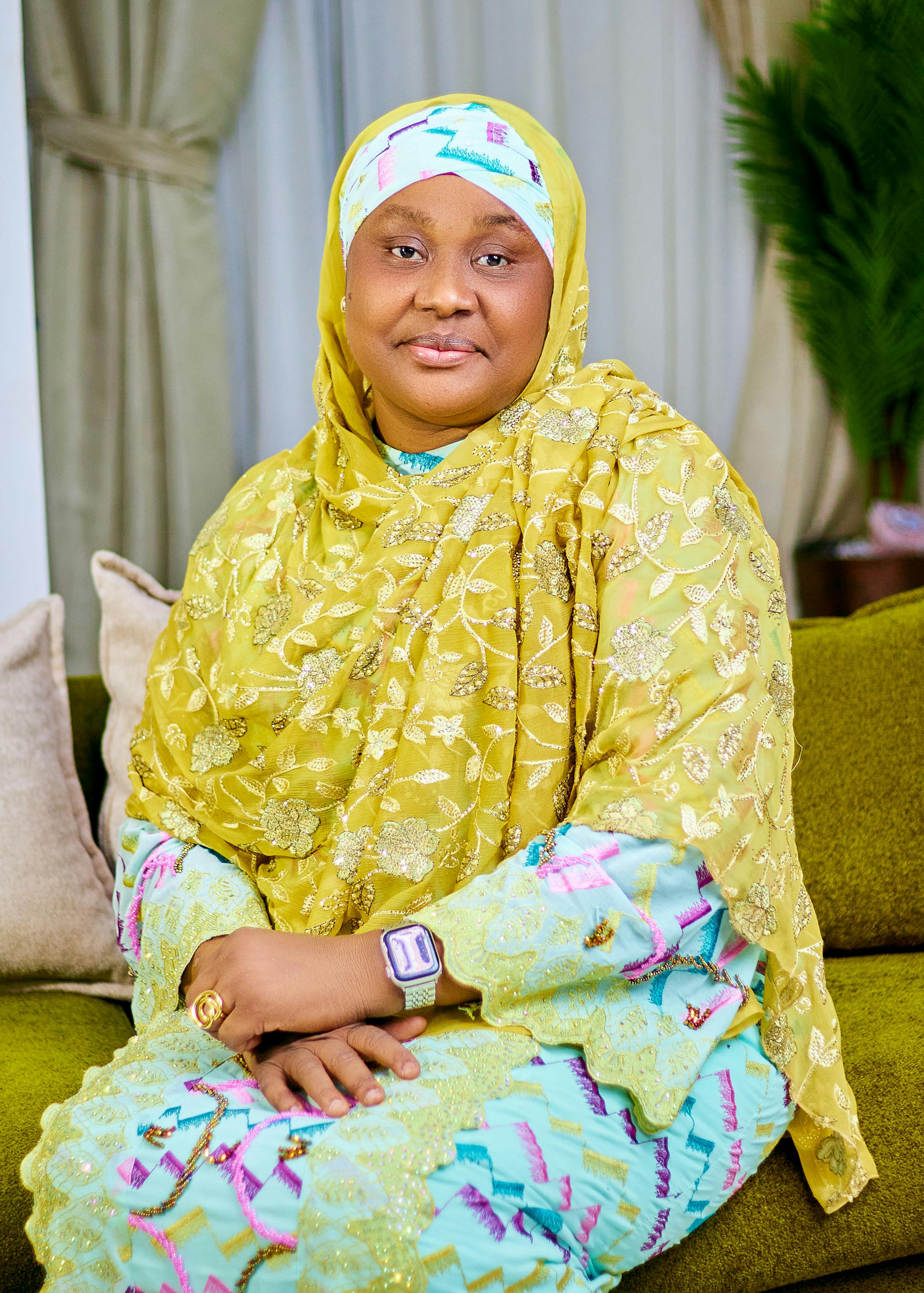 Portrait of a smiling woman in vibrant traditional Nigerian attire, indoors.