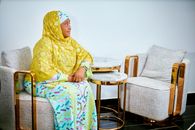 Elegant woman in traditional attire sitting in a modern indoor setting.