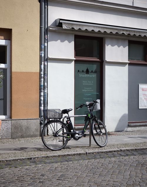 Free A bicycle parked against a storefront on a sunny street in Berlin, Germany, captures urban tranquility. Stock Photo