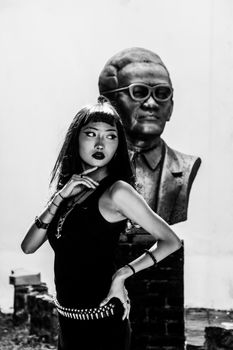 A striking black and white photo of a woman in front of a sculpture, highlighting artistic expression.
