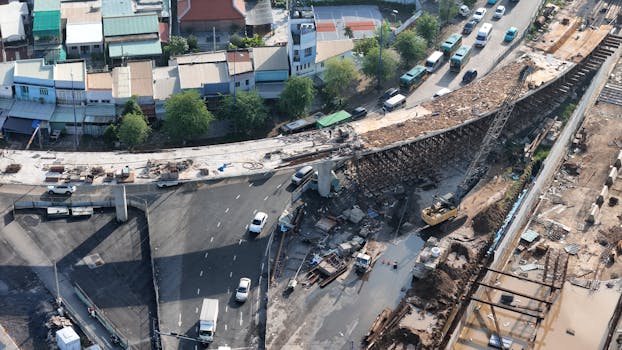 An aerial shot of a highway under construction with vehicles and machinery, showing urban development.