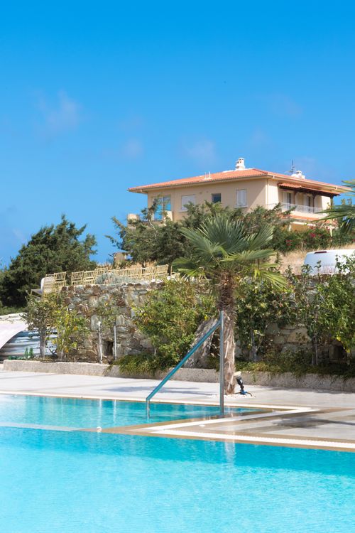 Free Elegant villa with a pool and palm trees under a bright blue sky. Stock Photo