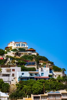 Scenic view of colorful villas on a cliff under a bright blue sky.