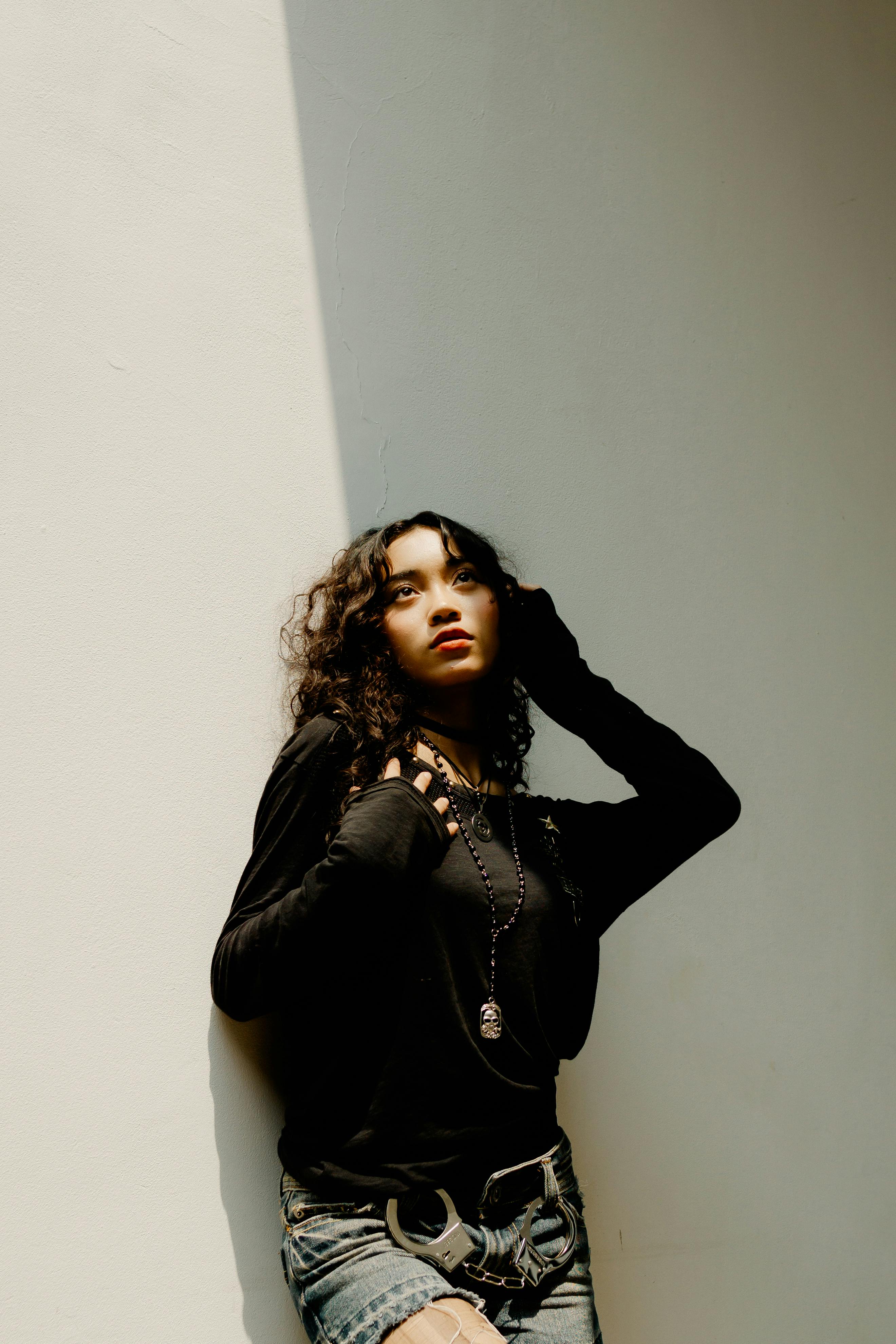 Young woman posing in sunlight outdoors in Bandung, Indonesia, capturing a fashionable moment.