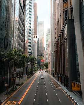 A view of Singapore's central business district with towering skyscrapers and an empty street.