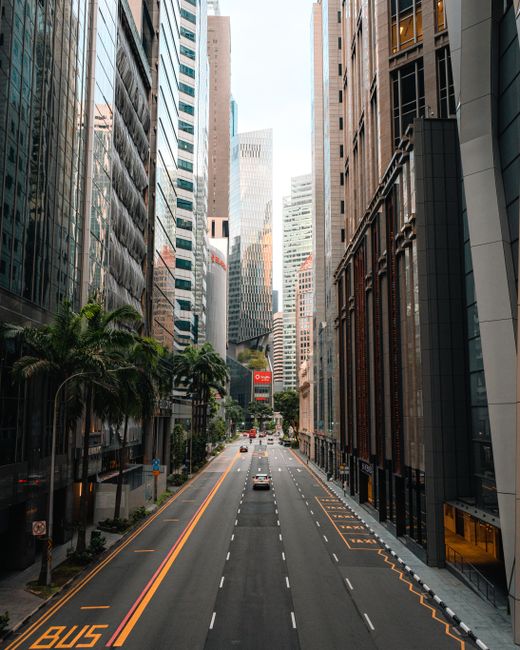 A view of Singapore's central business district with towering skyscrapers and an empty street.