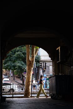 A captivating street scene in Tbilisi, Georgia, framed by a dark archway with a person walking by.