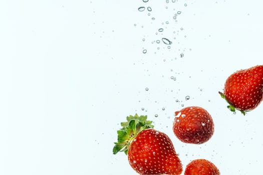 Vibrant strawberries submerged in water, showcasing freshness and motion.