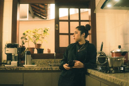 A woman stands in a kitchen holding a cup of coffee, creating a warm, intimate atmosphere.