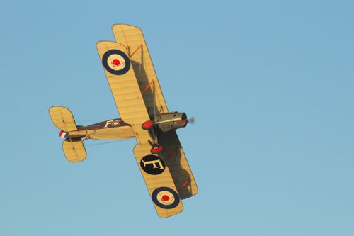 Free A historical biplane flying against a clear blue sky, showcasing vintage aviation design. Stock Photo