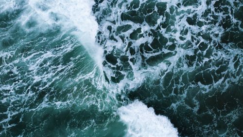 Free Dynamic aerial shot capturing the movement of ocean waves with frothy whitecaps. Stock Photo