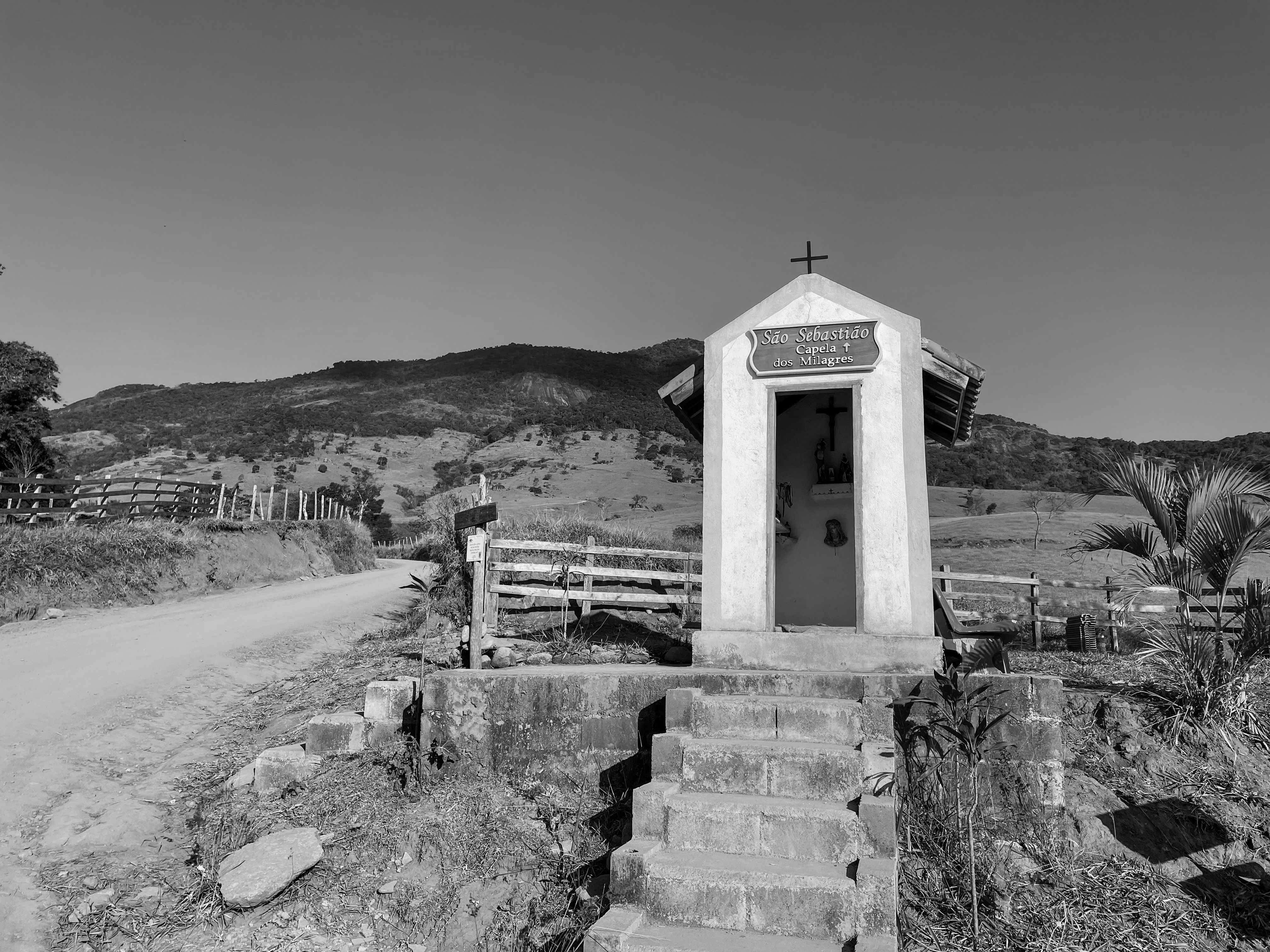 A serene rural chapel in São Paulo with mountain backdrop on a sunny day.