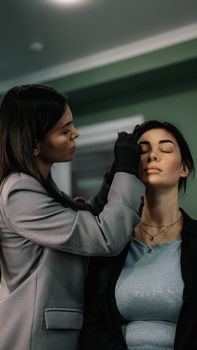 Makeup artist applying eyeshadow in a beauty salon. Indoor professional setting.