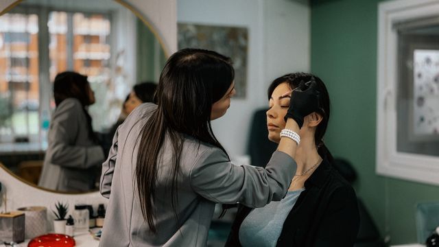 Maquilleuse professionnelle travaillant les sourcils d'une cliente dans un salon