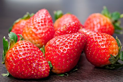 Free Vibrant fresh strawberries arranged on a wooden table, showcasing their natural texture. Stock Photo