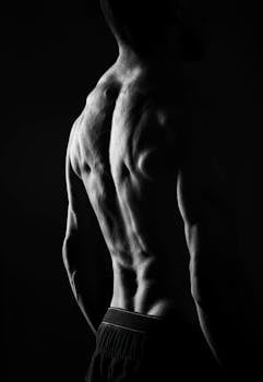 Dramatic silhouette of male back muscles in black and white photography.