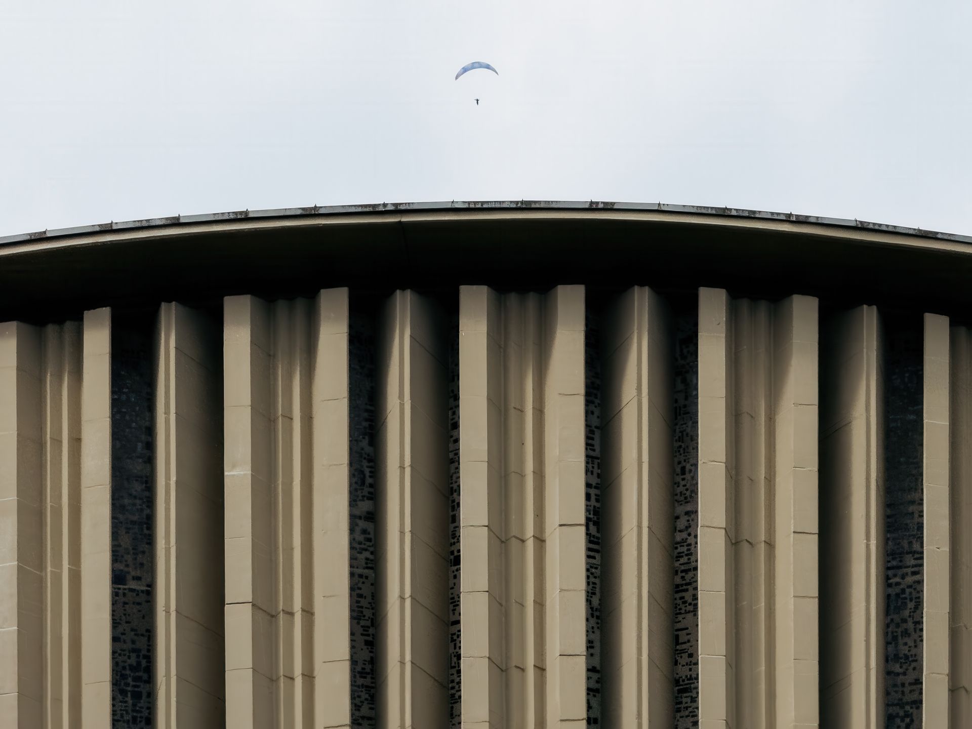 Captivating view of a parachutist above a modern architectural building.