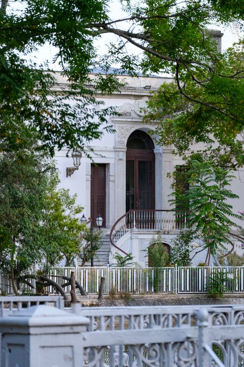 Free An elegant old mansion surrounded by greenery and trees, showcasing vintage architecture. Stock Photo