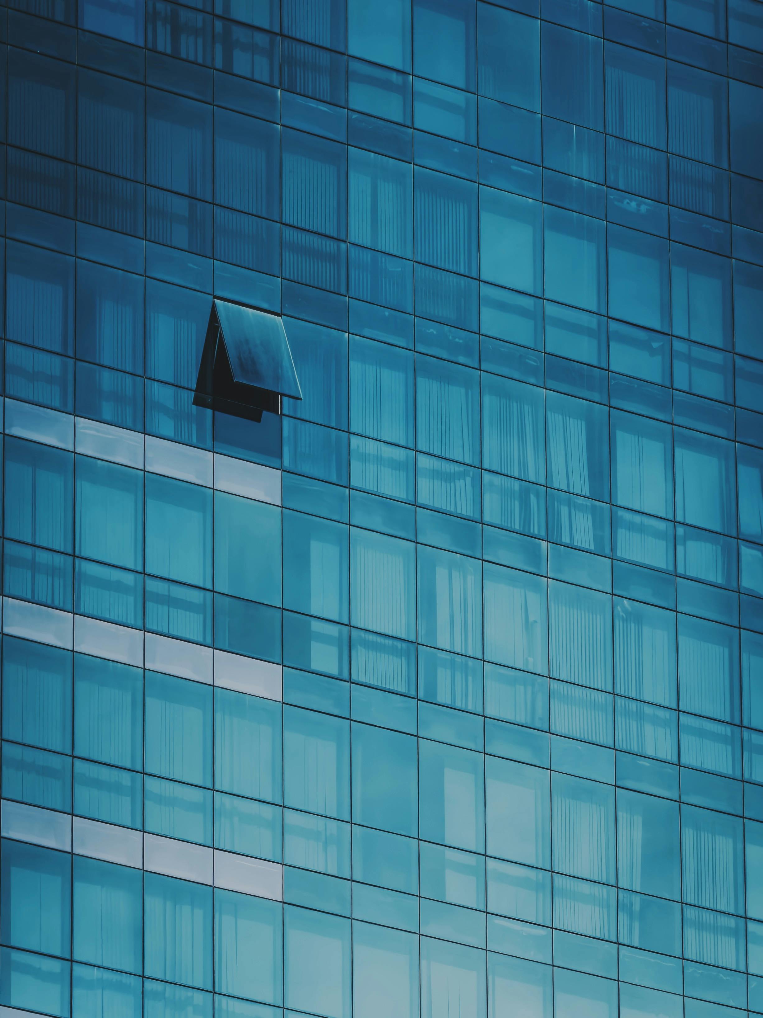 Gratis Una llamativa fachada de edificio de vidrio azul con una ventana abierta que ofrece un contraste arquitectónico único. Foto de stock