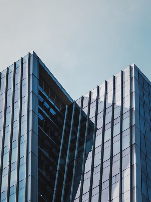Free Stunning close-up of a modern glass skyscraper's architectural lines against a clear blue sky. Stock Photo