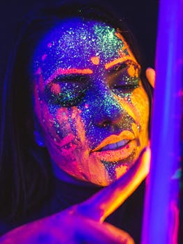 Vibrant portrait of a woman with neon and UV glow paint, captured in darkness.