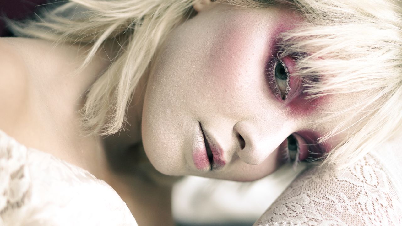 close up portrait of a woman with striking makeup and blonde hair emph