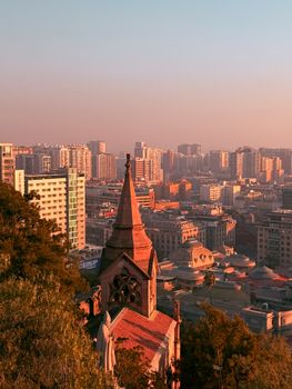 Scenic cityscape featuring a historic tower with modern buildings at sunset.