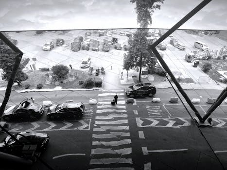 Aerial view of a bustling street in Sarajevo, featuring cars and pedestrians in a black-and-white composition.