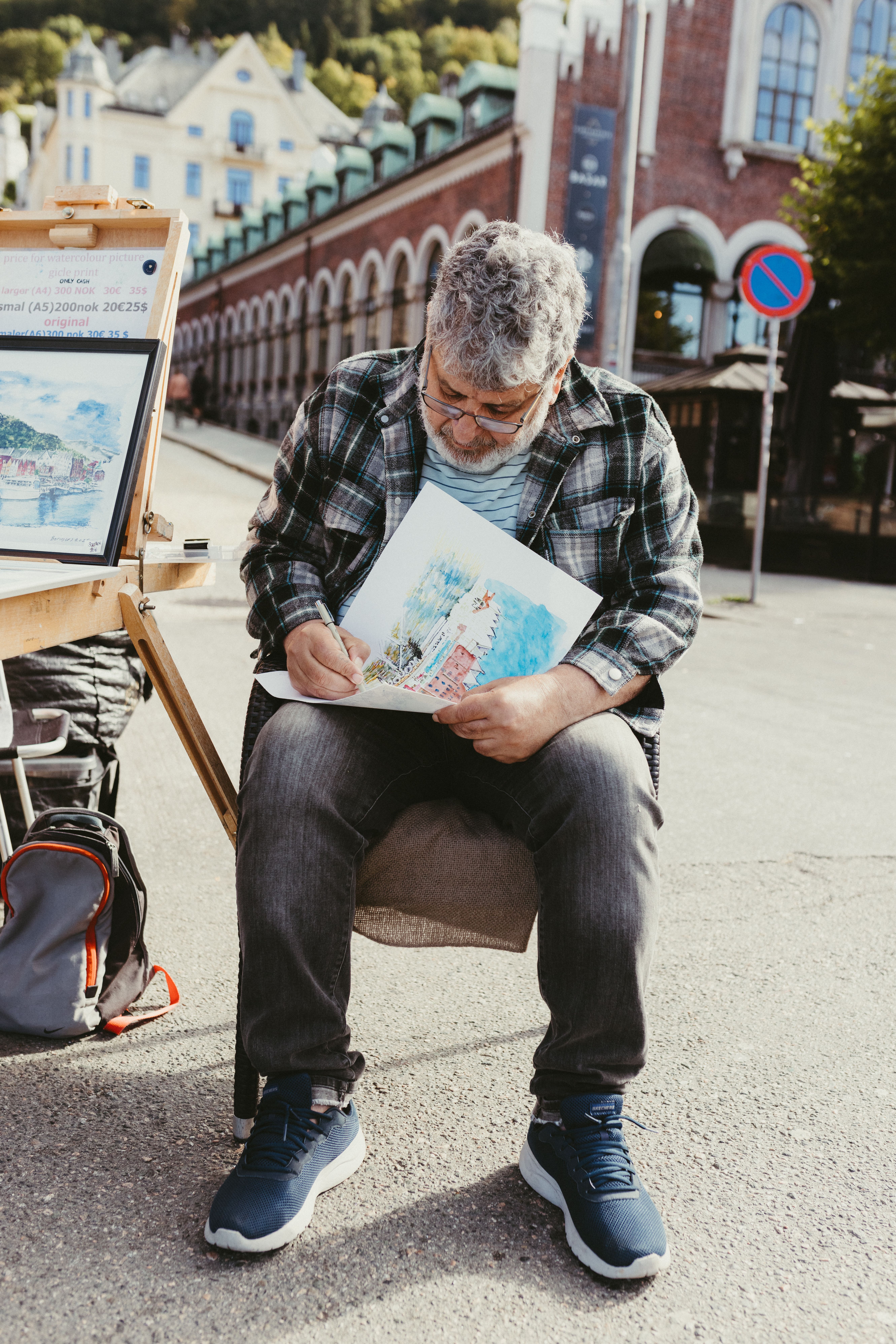 A street artist in Bergen, Norway creates vibrant art on the busy streets, captivating passersby.
