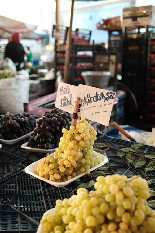 Free Yellow and black grapes on display with price signs at an outdoor market. Stock Photo