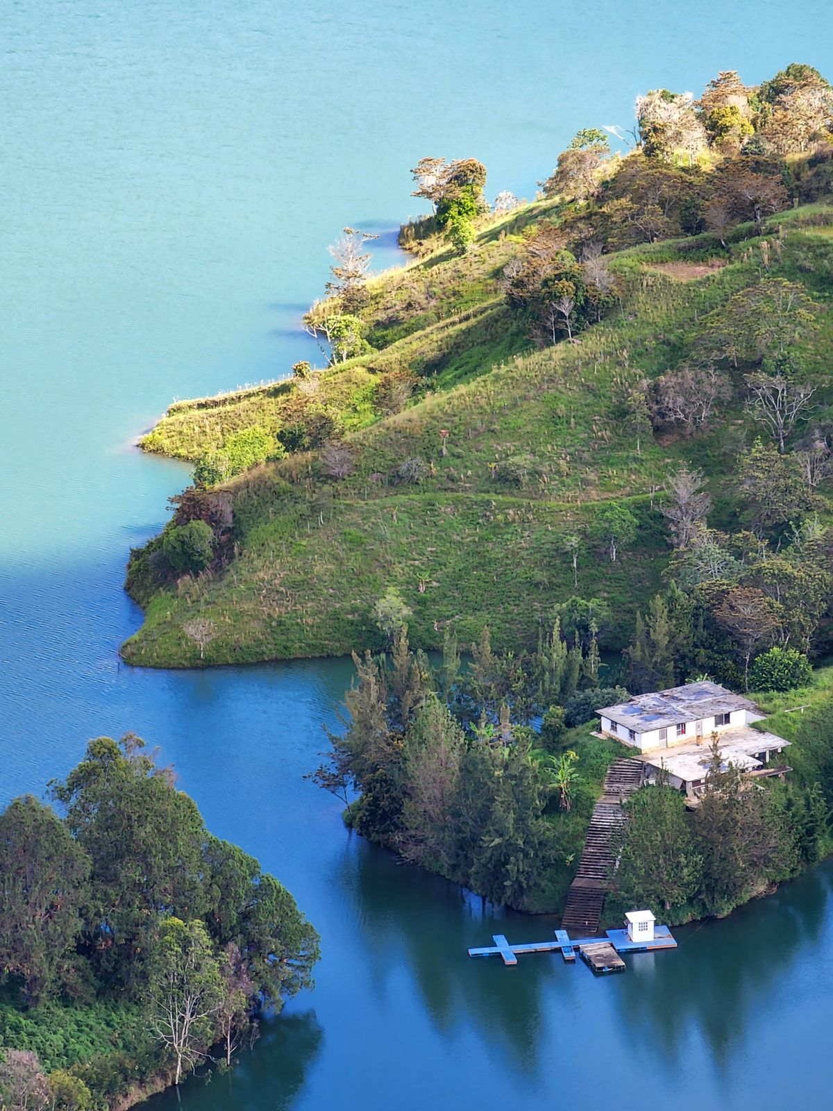 Aerial view of a lakeside house surrounded by trees and calm water, the kind of wooded shoreline setting found around North Muskegon