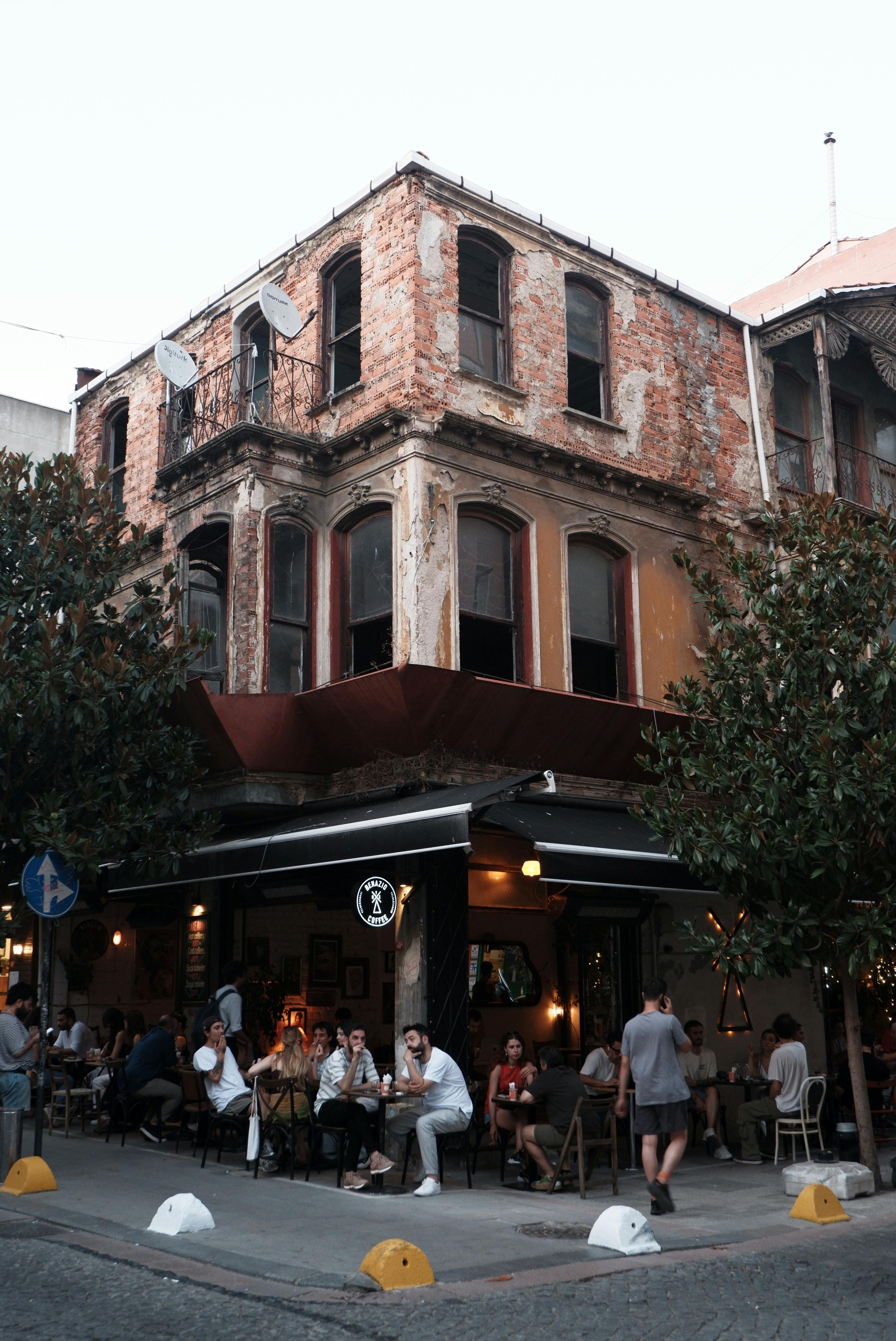 Free Cozy outdoor cafe on the corner of a historic, weathered building during daytime. Stock Photo