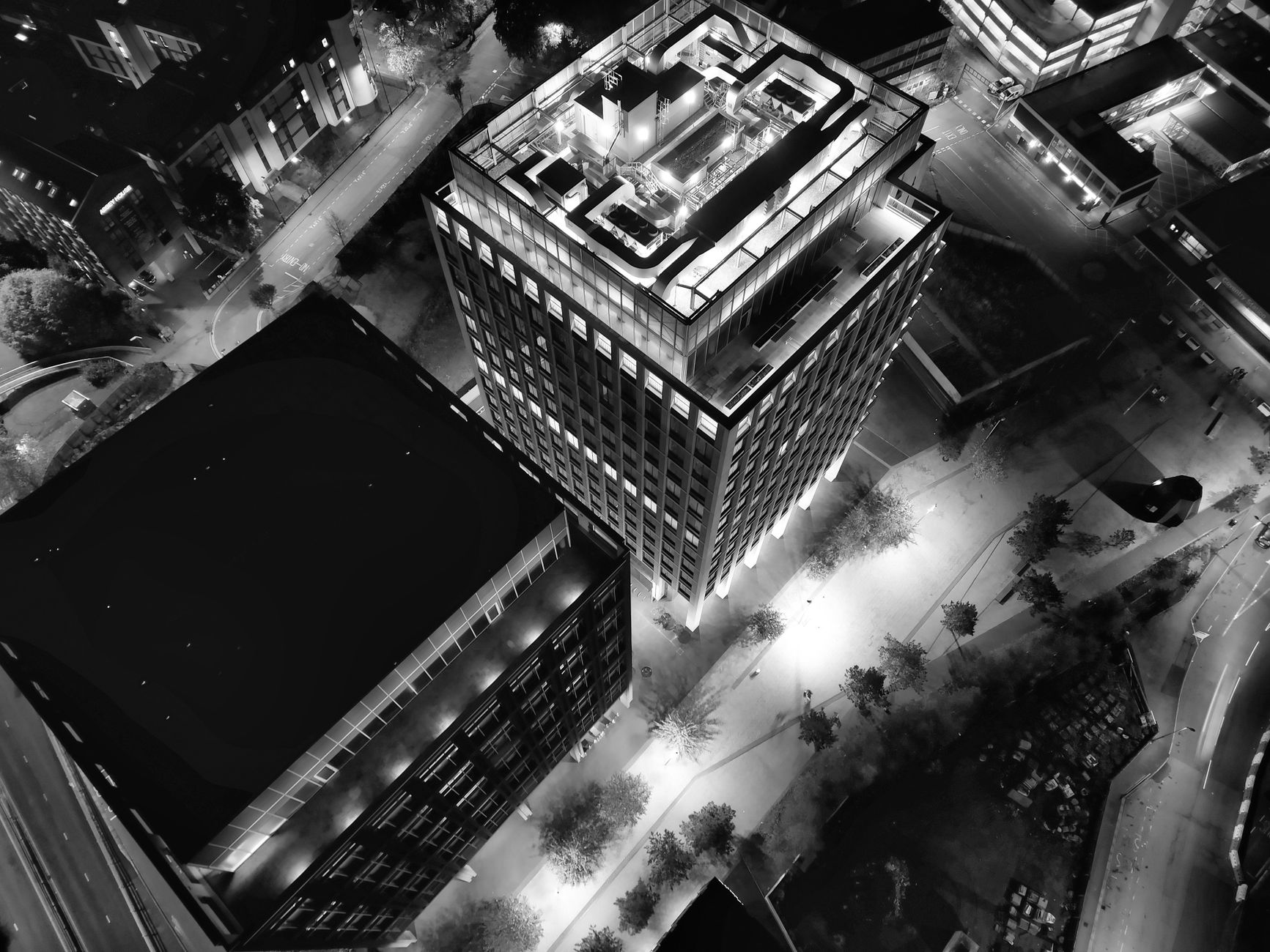 Aerial shot of a brightly lit skyscraper in an urban setting at night, showcasing architectural design.