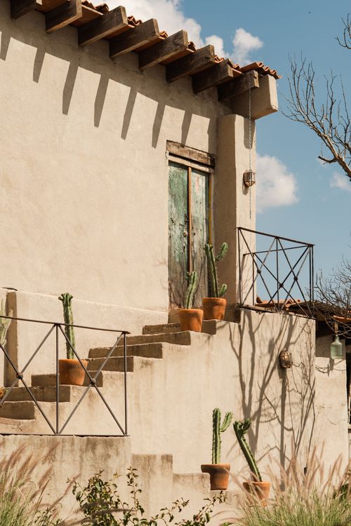 Gratis Affascinante esterno rustico di una casa in adobe con cactus in vaso, immortalato nella calda luce del sole. Perfetto per immagini di viaggio o lifestyle. Foto a disposizione