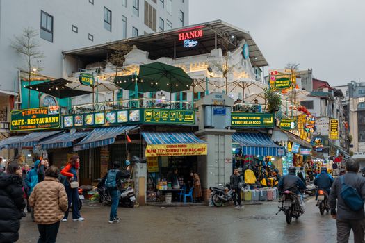 Explore the lively streets of Hanoi, Vietnam, bustling with vendors, cafes, and vibrant signs.