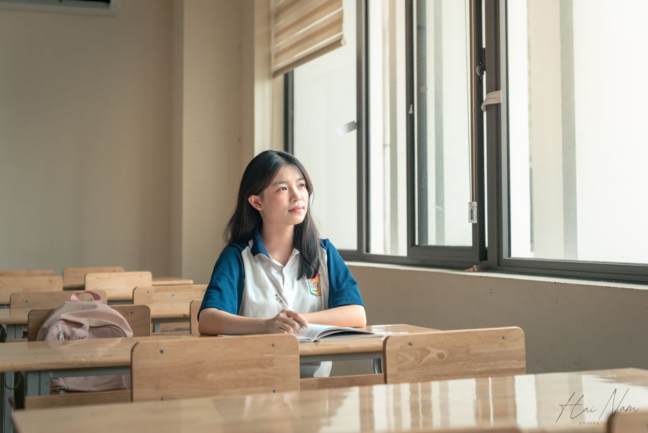 A student sits alone in a classroom, gazing out the window, contemplating. Bright natural light fills the room. A student sits alone in a classroom, gazing out the window, contemplating. Bright natural light fills the room.