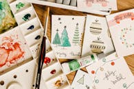 木制桌子上摆放着艺术节日卡片设计、水彩颜料和刷子