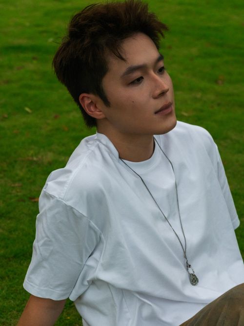 Free Casual portrait of a young man sitting on lush green grass, enjoying a peaceful outdoor moment. Stock Photo