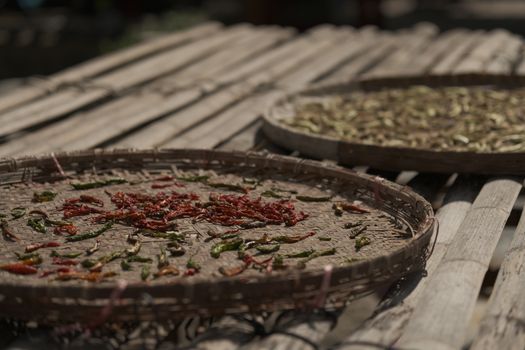 Sun-dried chili peppers on bamboo trays showcasing traditional drying methods.