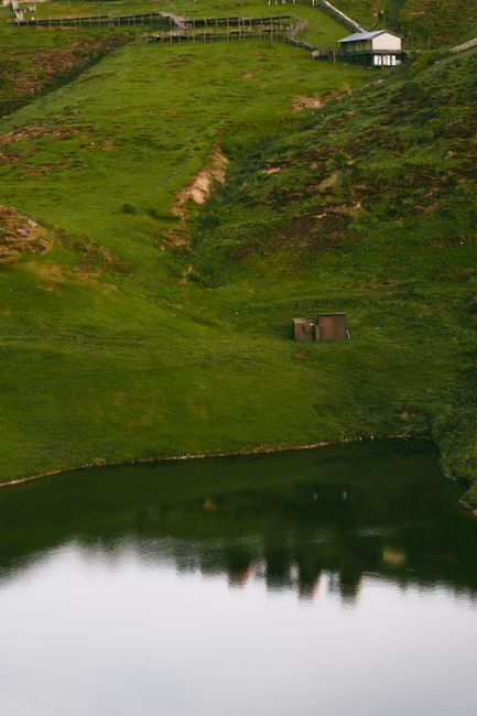 Peaceful landscape of lush green hills and a calm reflective lake.