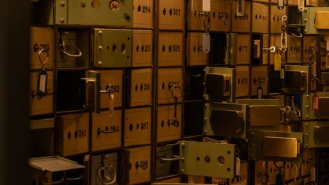 A dimly lit room filled with vintage security deposit boxes and keys, evoking mystery.